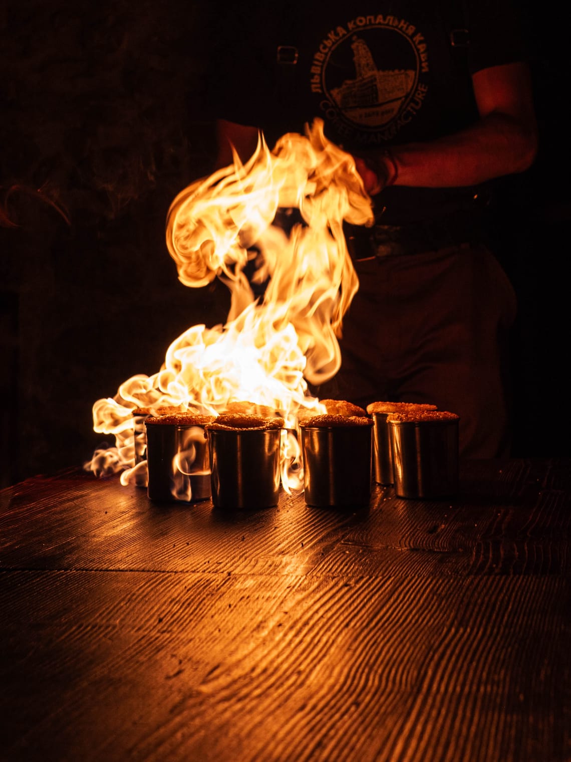 A person with a blowtorch (not visible) sets fire to mugs of hot chocolate to create a brûlée surface.