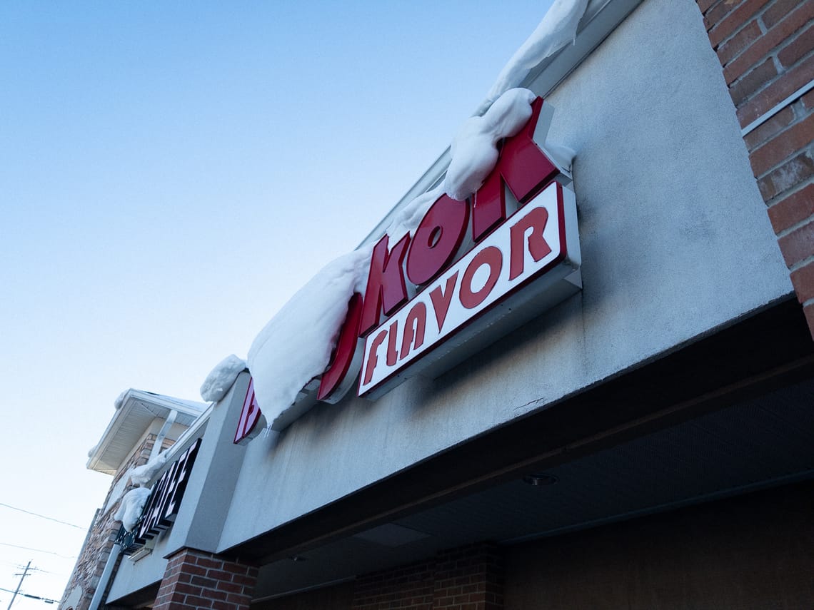 A snow-covered business sign covering up the words "Bangkok" and only leaving "flavor" visible.